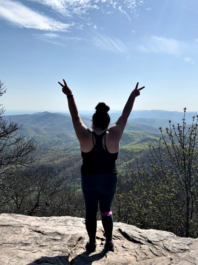 The back of a woman standing on the summit of Blood Mountain.