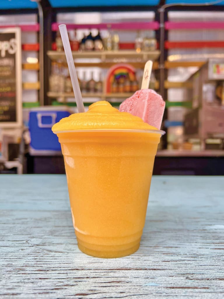 A vibrant orange frozen drink with whipped cream and a popsicle garnish in Atlanta, Georgia.