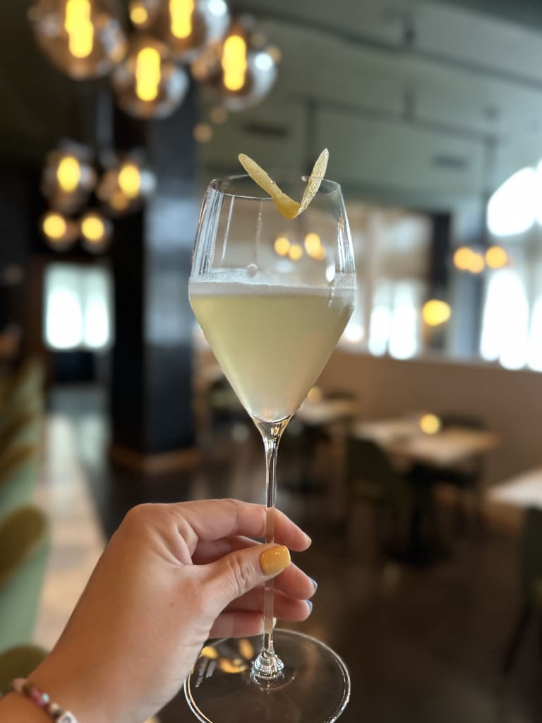 Bebidas de Verano en Atlanta 7 A hand holds a martini glass with a yellow drink and lemon peel garnish in Atlanta, Georgia.