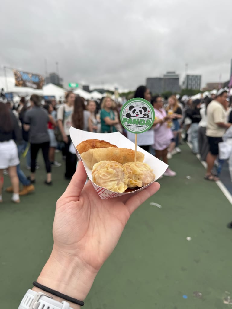 Cool Things To Do in September in Atlanta 1 Hand holding a tray of dumplings with a panda-themed toothpick at a crowded outdoor event in Atlanta, Georgia.