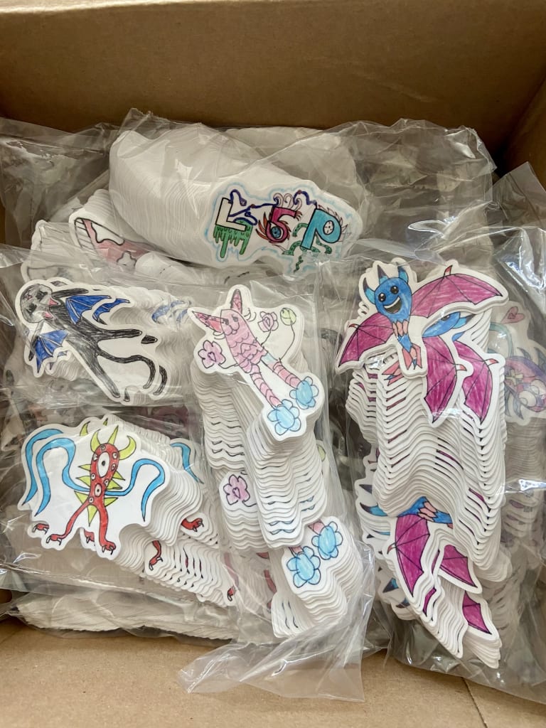 A box filled with colorful, hand-drawn stickers of various fantastical creatures in Atlanta, Georgia.
