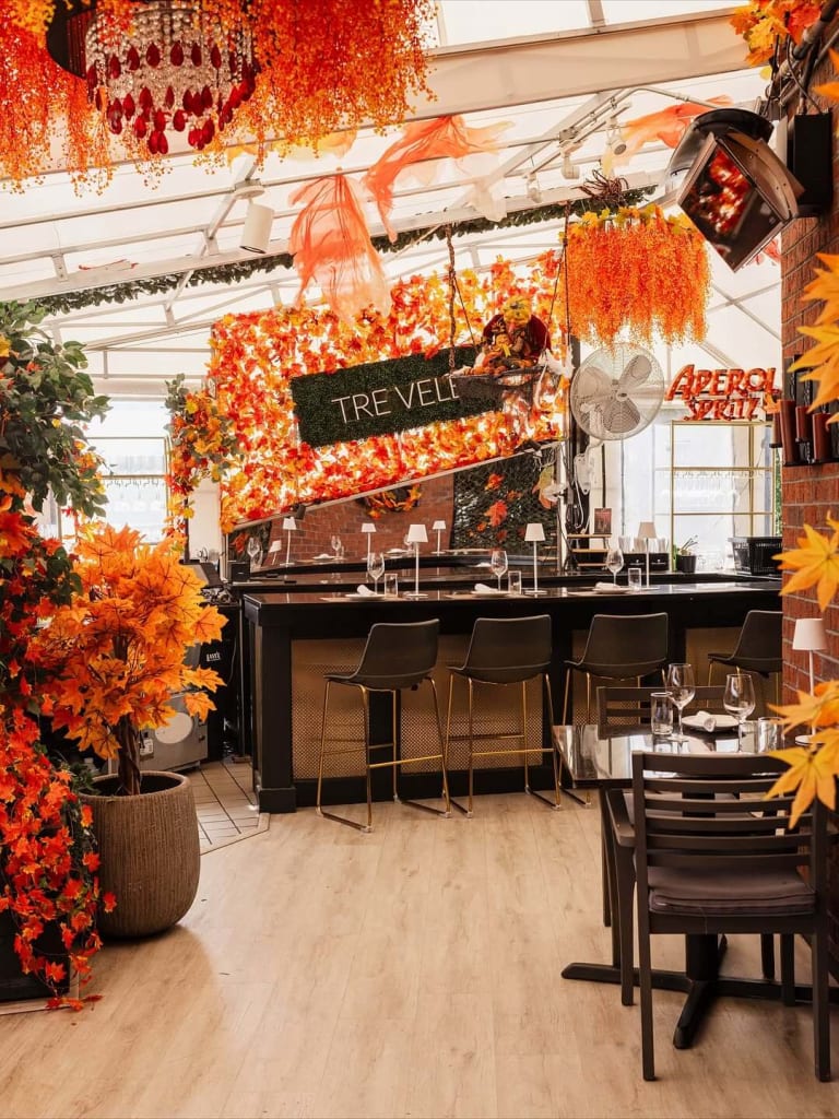 Warm up at the Best Restaurants for Cozy Winter Dining in Atlanta 8 A vibrant restaurant interior with autumnal orange and red foliage decorations in Atlanta, Georgia.