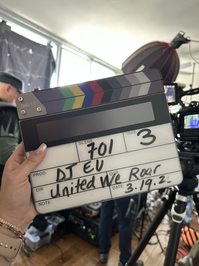 A hand holds a clapperboard with the scene number 701 and take 3, in a film or video production studio in Atlanta, Georgia.