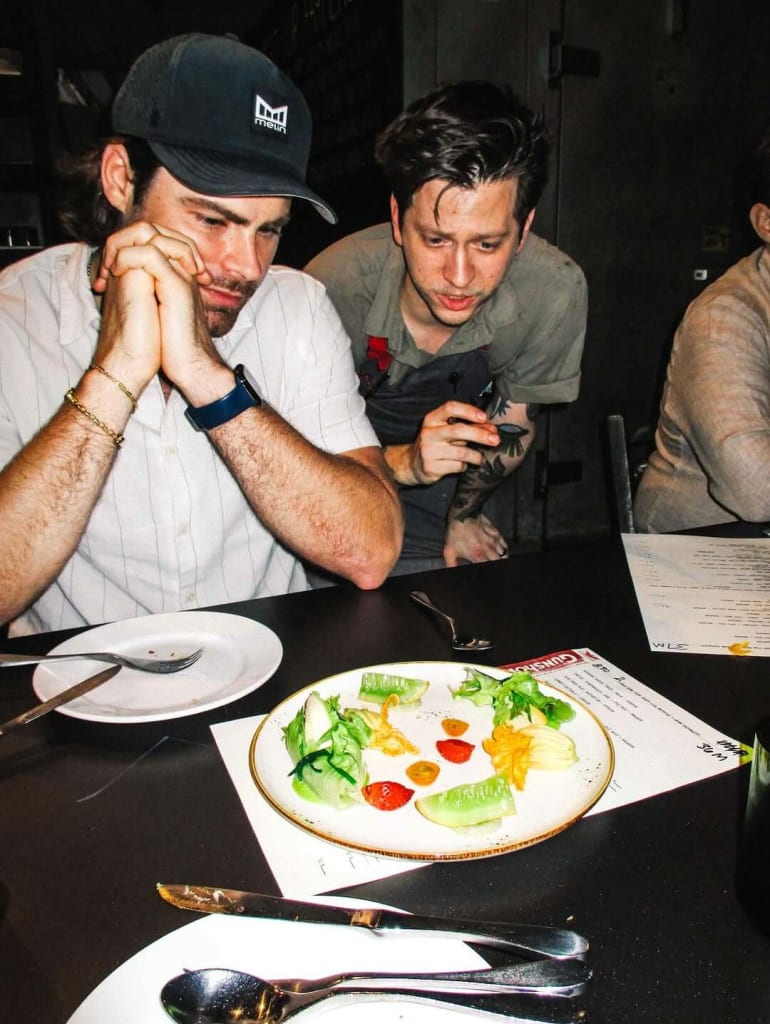 Two men in a restaurant, one with a plate of colorful salad and the other with a smartphone in Atlanta, Georgia.