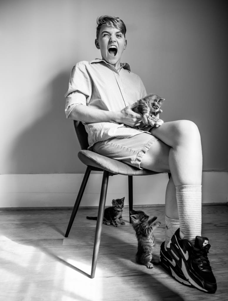A person sitting on a chair with three kittens, one in their lap and two on the floor in Atlanta, Georgia.