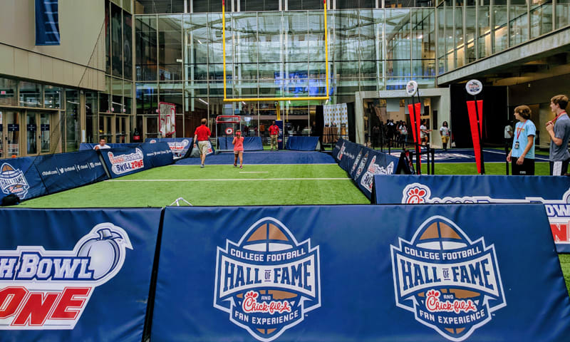 O Melhor Roteiro pelo Centro da Cidade: Aonde ir e o que Fazer 4 Indoor artificial turf field with banners for College Football Hall of Fame and Chick-fil-A Fan Experience in Atlanta, Georgia.