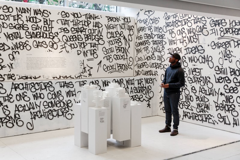 A man standing in the "Close to the Edge: The Birth of Hip-Hop Architecture" exhibit at MODA.