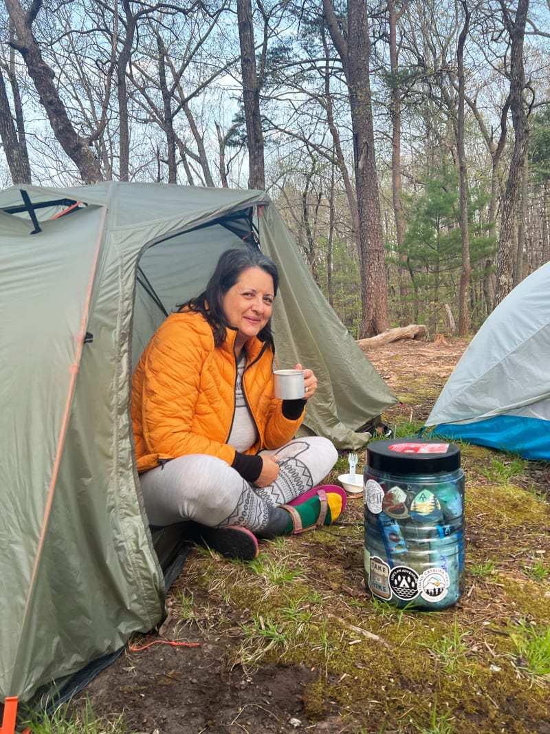 A woman smiling and sitting in the door of her tent while backpacking in Georiga.