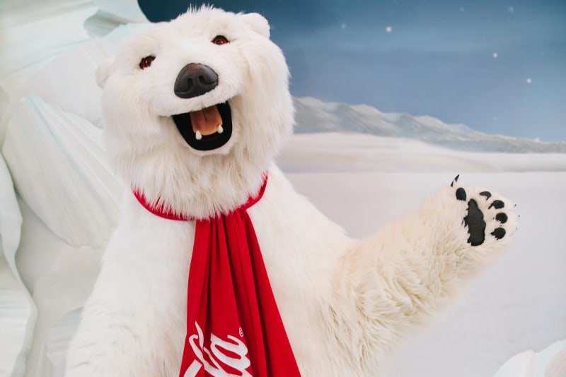 O Melhor Roteiro pelo Centro da Cidade: Aonde ir e o que Fazer 3 A costumed polar bear mascot wearing a red Coca-Cola scarf waves cheerfully in Atlanta, Georgia.