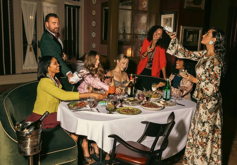 A diverse group of friends enjoys a festive dinner party with wine and laughter in Atlanta, Georgia.