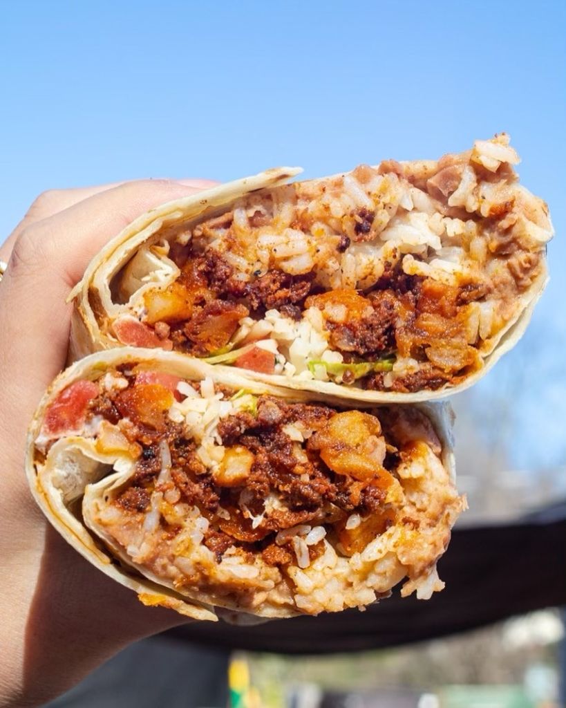 A hand holding up a stuffed chorizo burrito from Chef Yvette at the Gorditas ATL pop-up.