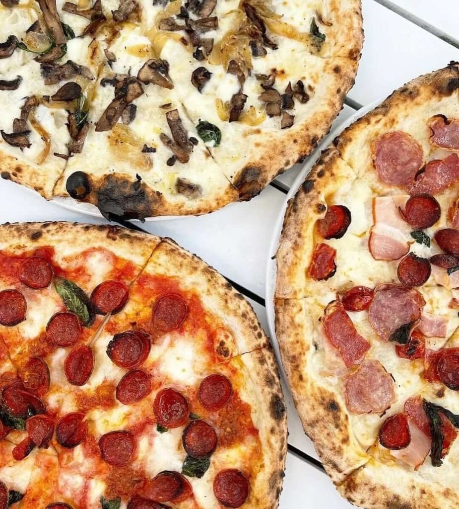 Warm up at the Best Restaurants for Cozy Winter Dining in Atlanta 9 Four artisanal pizzas with various toppings, including mushrooms, pepperoni, and prosciutto, on a white table in Atlanta, Georgia.