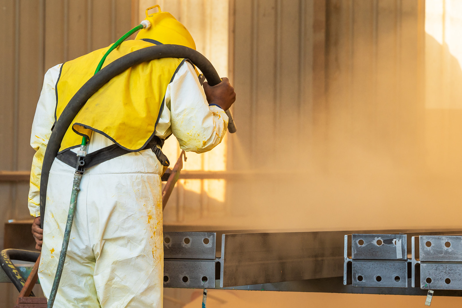 Worker performing industrial sandblasting services on steel components in Appleton, WI.