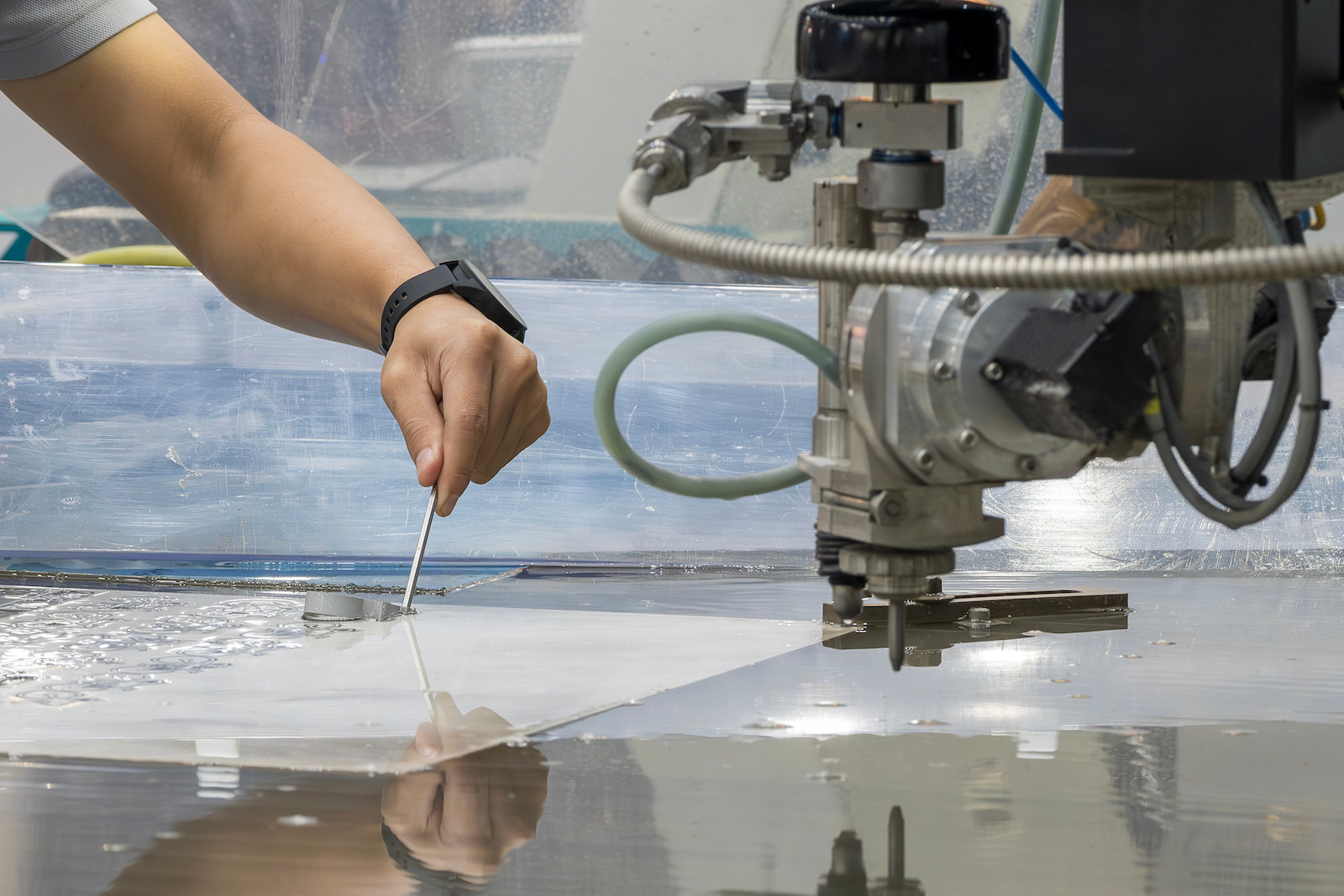Technician operating industrial waterjet cutting equipment for precision metal fabrication in Appleton, WI.