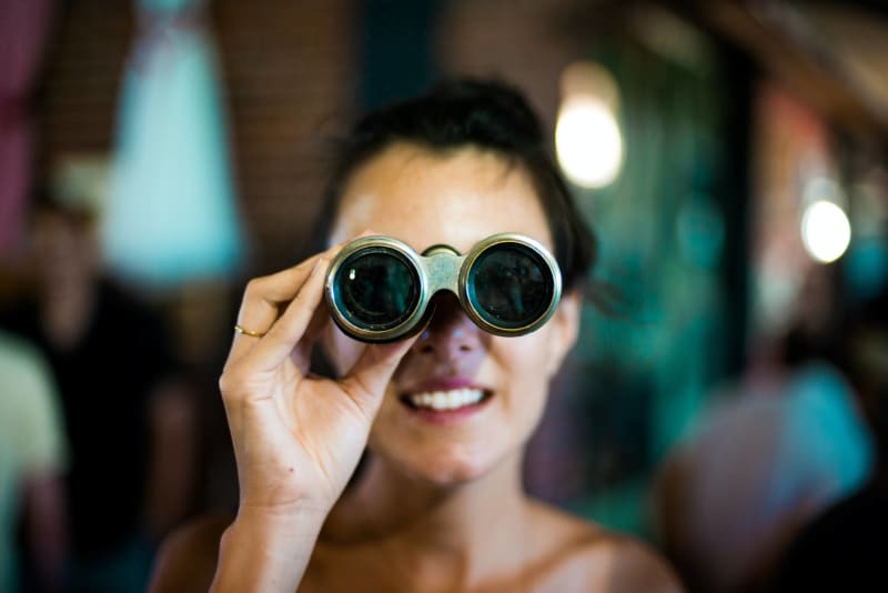 A woman looking through binoculars searching for something. Content creation requires a focus on search intent for best results. (https://unsplash.com/photos/T69h1_YfR-w).