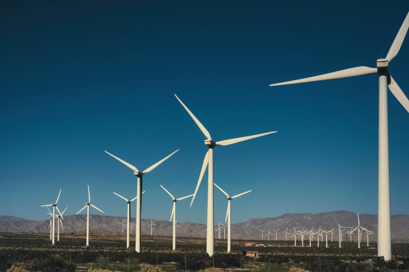Wind turbines against a bright blue sky. (Photo by Alfo Medeiros: https://www.pexels.com/photo/landscape-of-a-wind-farm-15268778/)