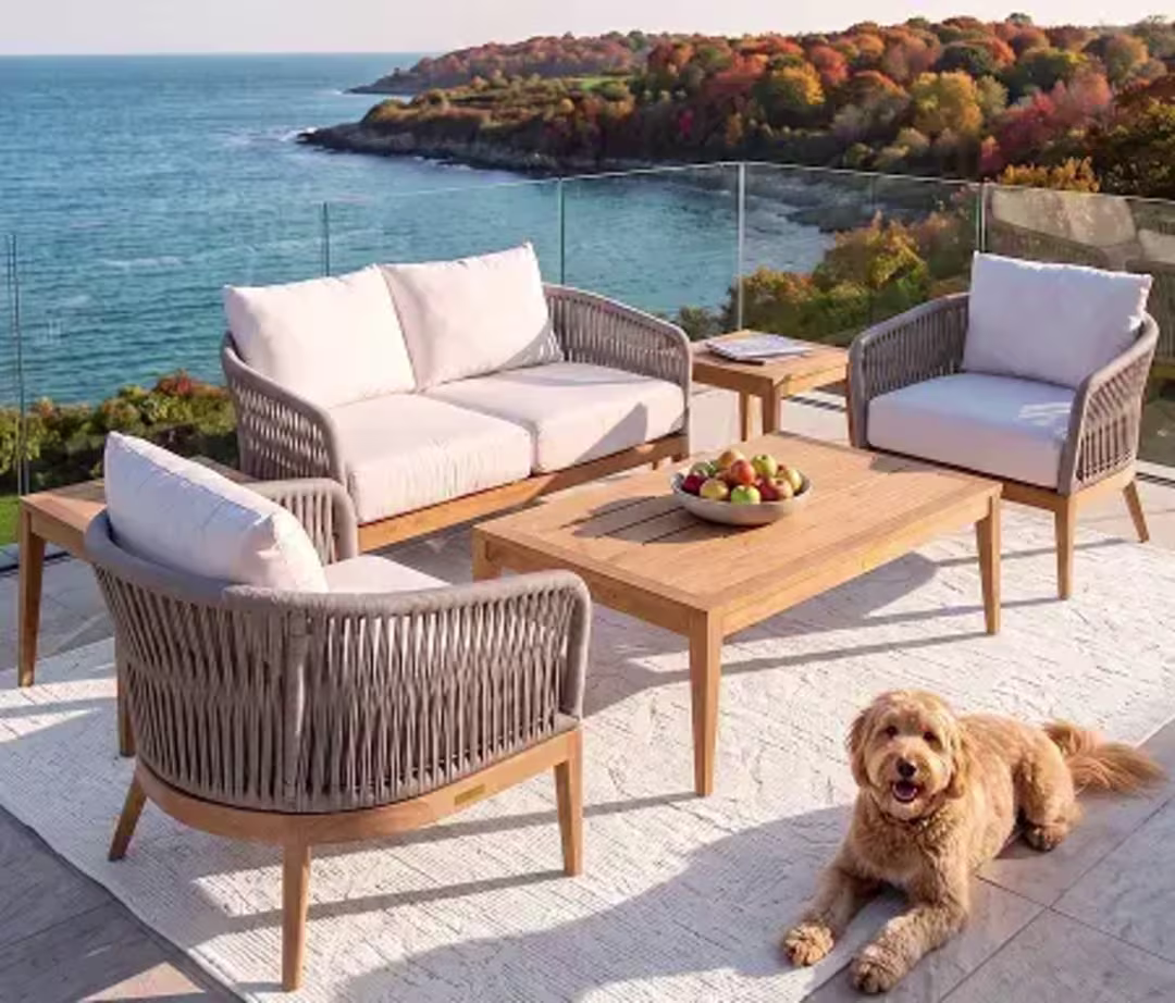 Woven outdoor seating set with a coffee table and dog on a waterfront patio.
