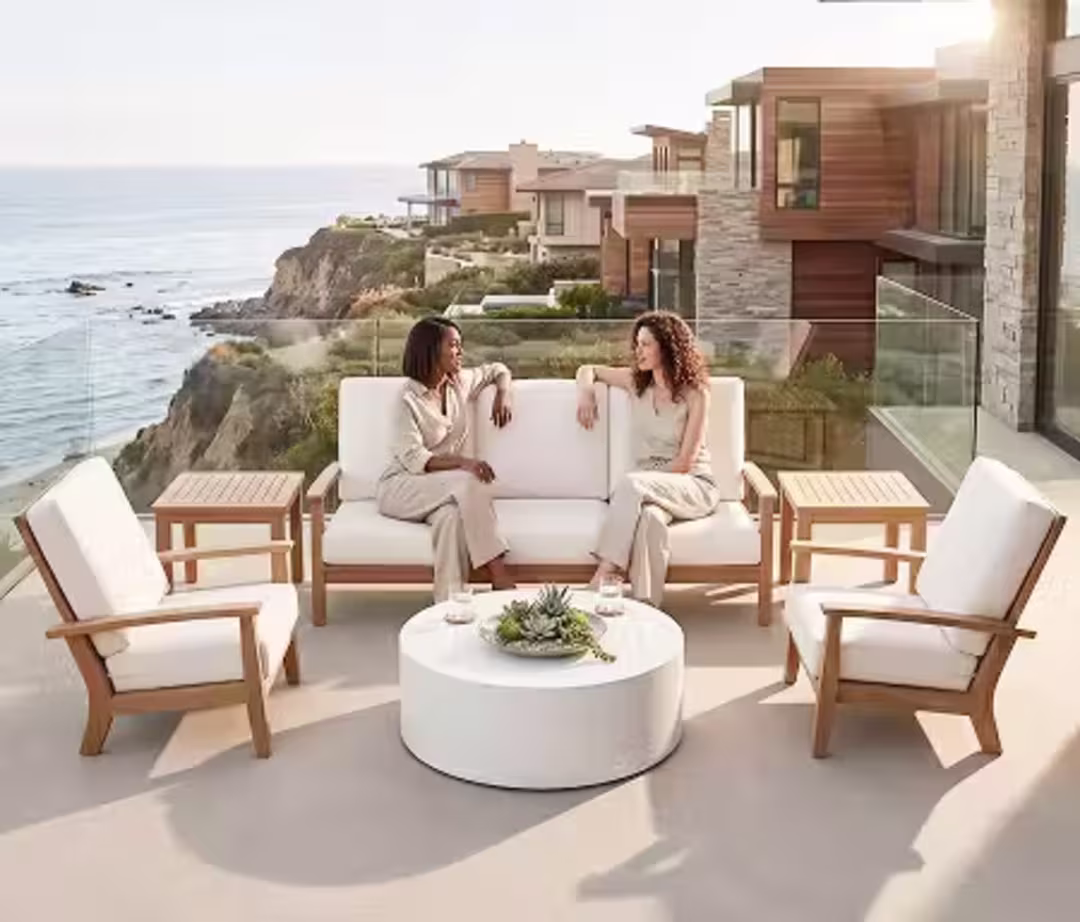 Two women chatting on a contemporary outdoor lounge set overlooking the ocean.