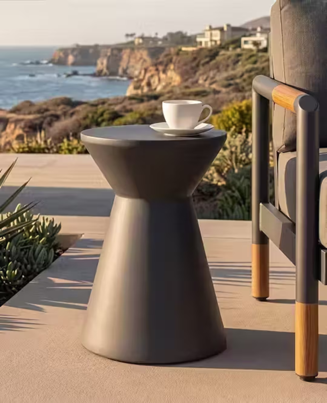 Contemporary outdoor side table with a coffee cup beside a lounge chair overlooking the ocean.