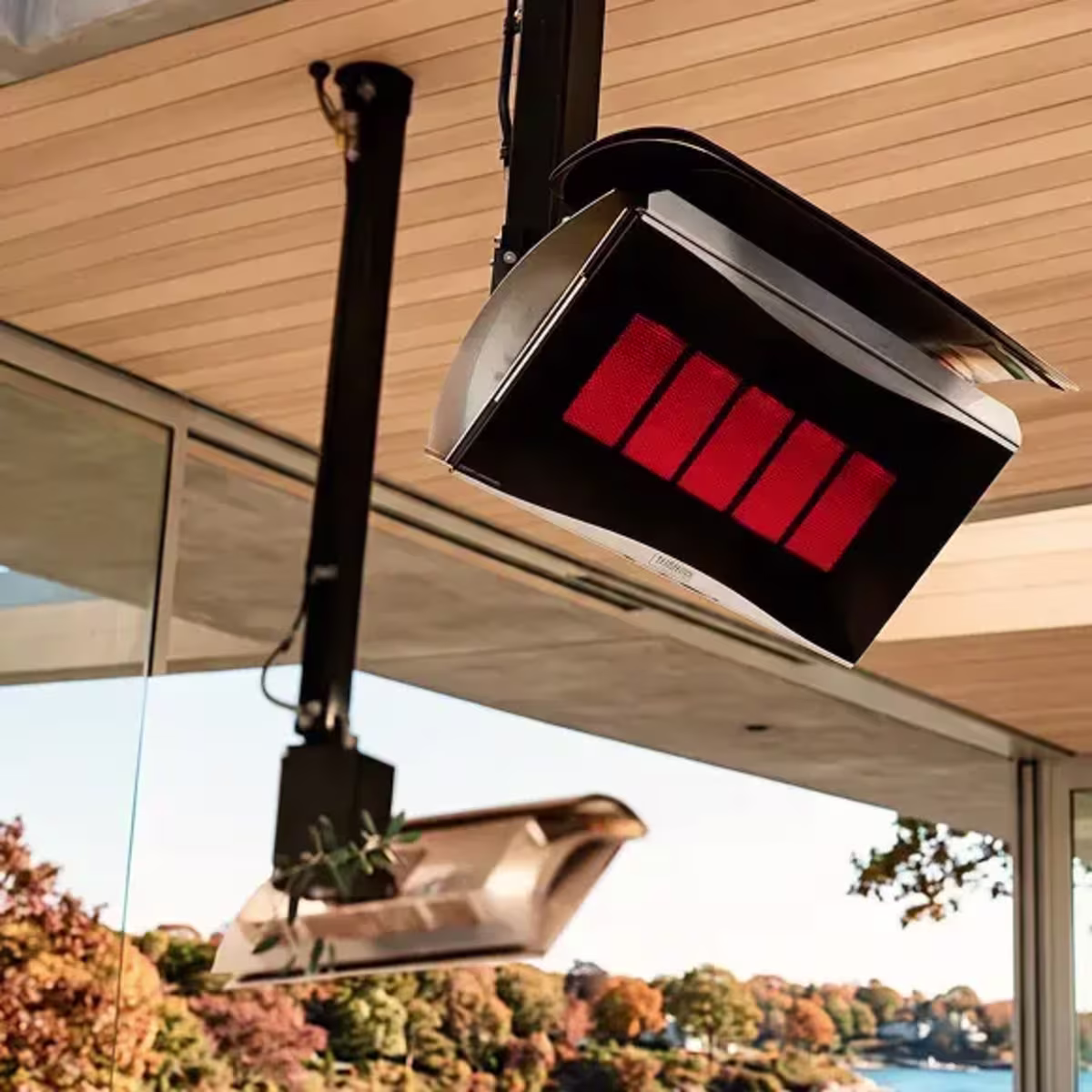 Close-up of glowing suspended patio heaters mounted beneath a covered outdoor space.