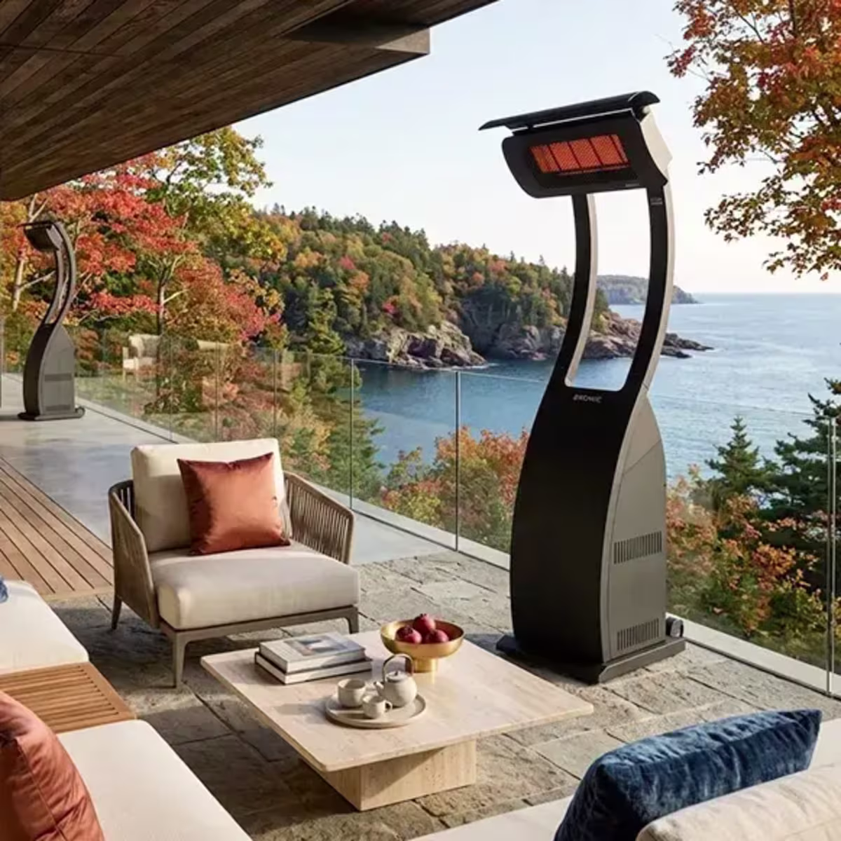 Freestanding patio heaters surrounding an outdoor lounge overlooking a rocky coastline.