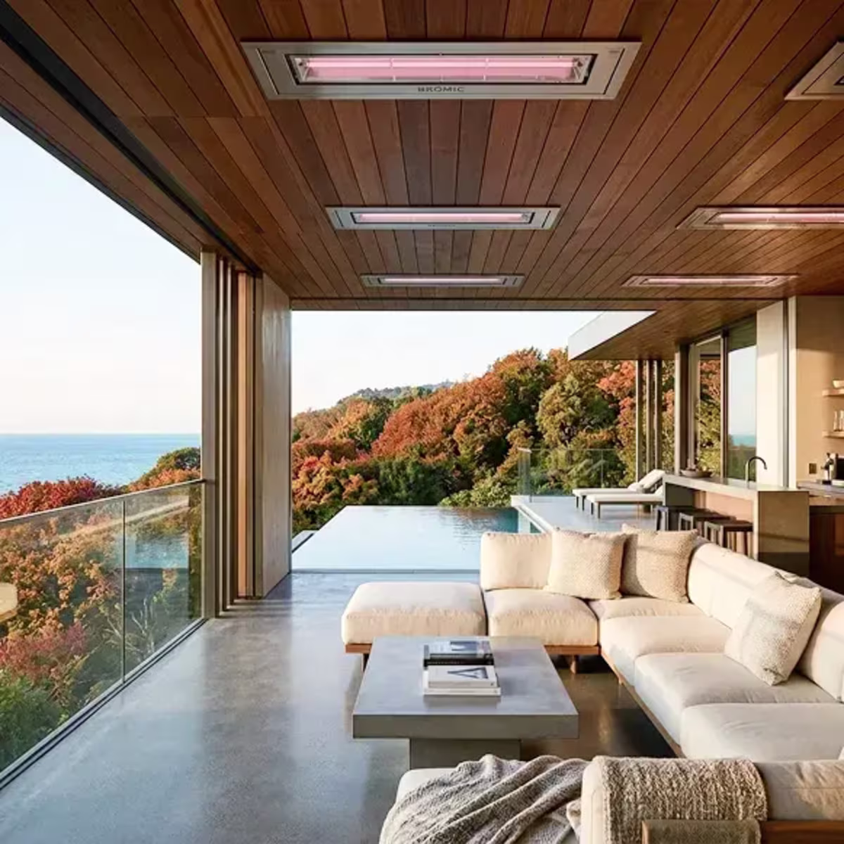 Recessed patio heaters above a sectional sofa on a covered terrace overlooking an infinity pool.