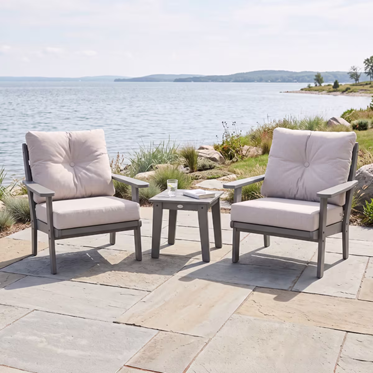 Two cushioned patio chairs beside lake.