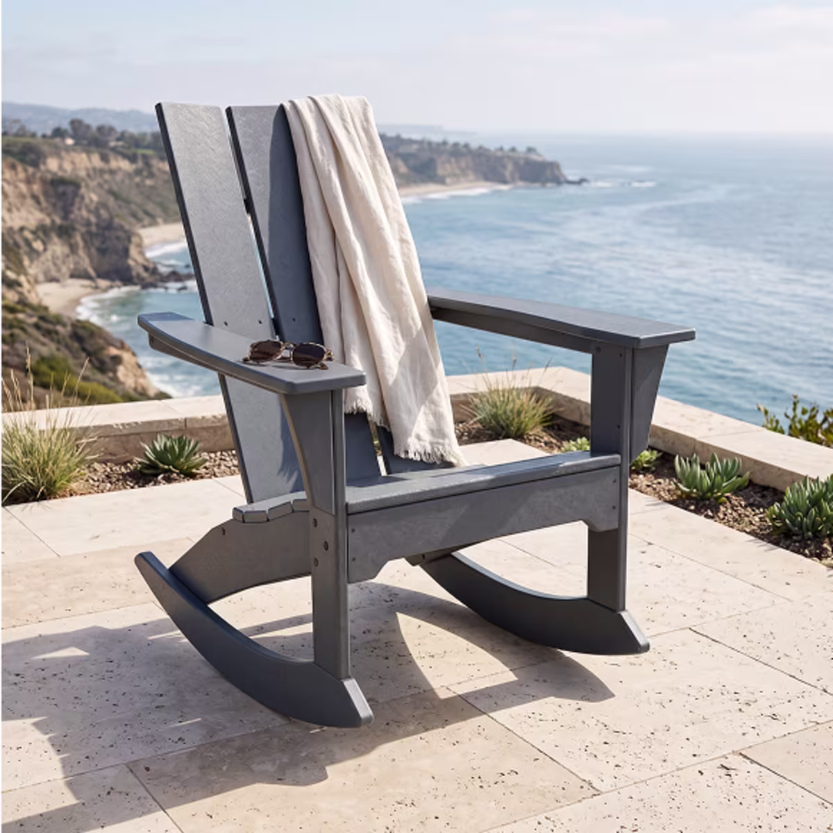 Gray Adirondack rocking chair overlooking sea.