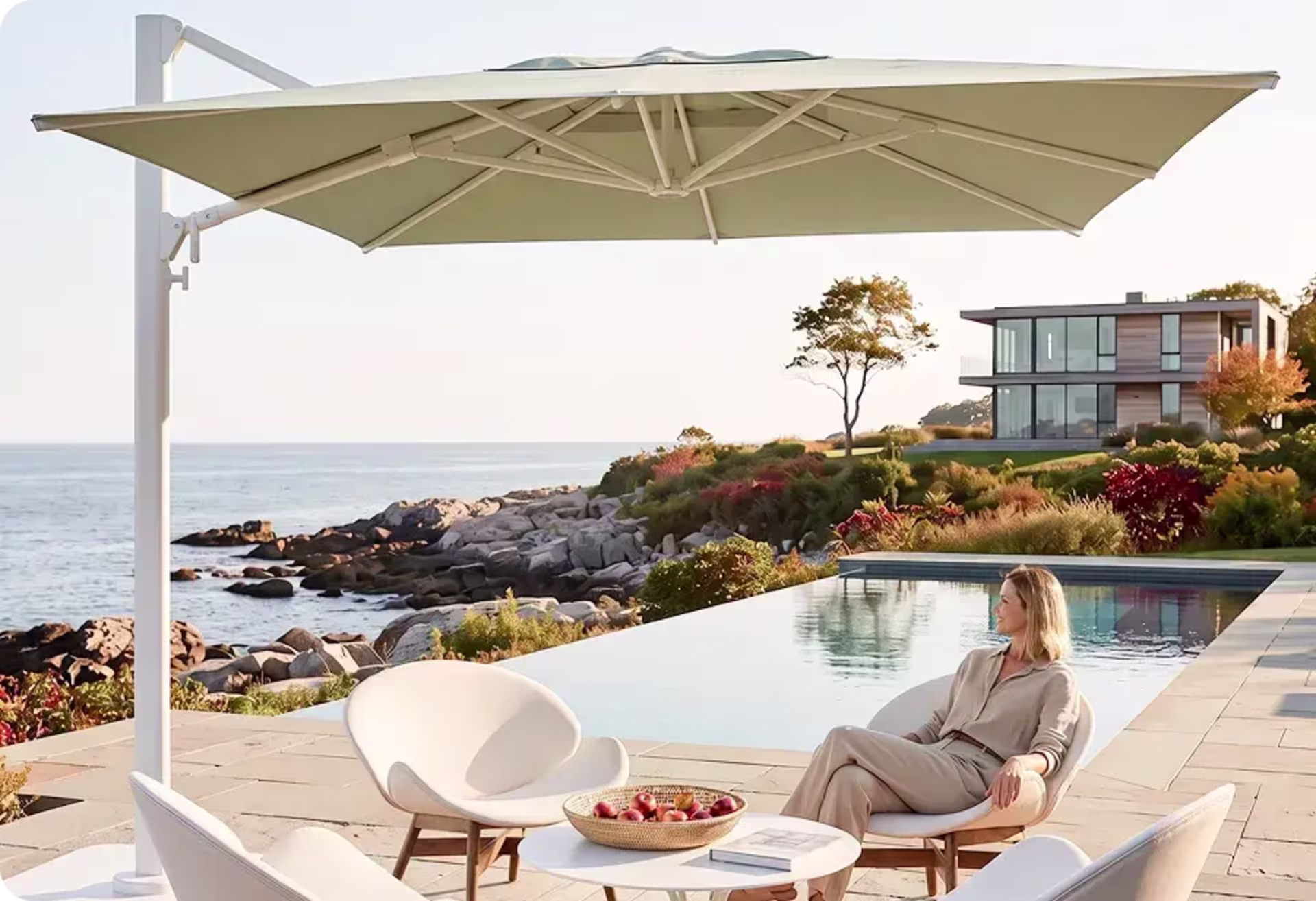 Large cantilever umbrella shading a poolside seating area overlooking the rocky coastline. image