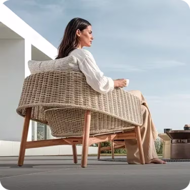 Woman relaxing in woven patio chair.
