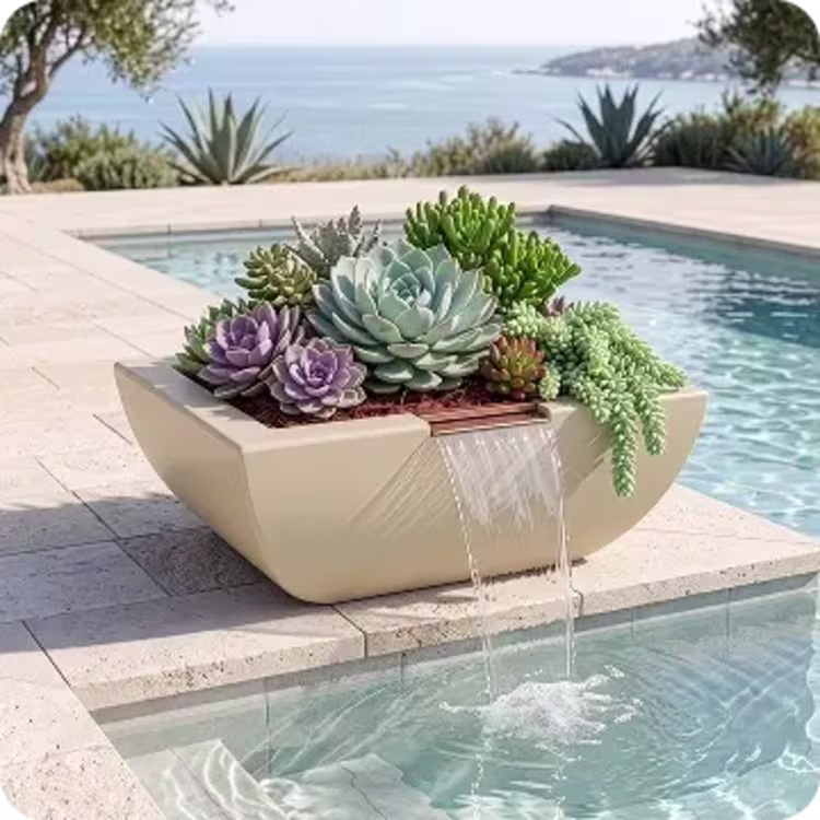 A square, beige planter bowl filled with various green and purple succulents sits poolside, cascading a clear sheet of water from a built-in copper spout directly into the swimming pool.