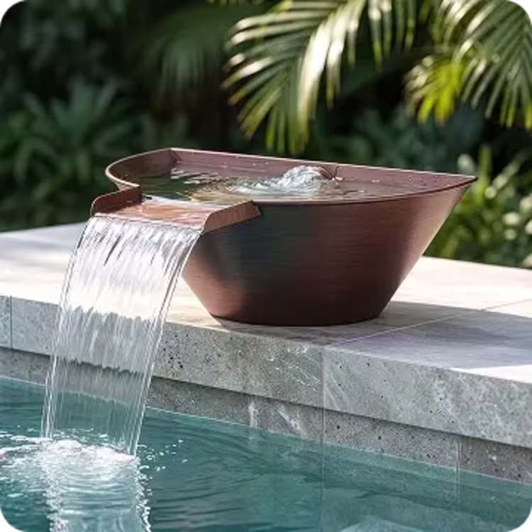 A bronze-finished, semi-circular metal pool scupper rests on a stone edge, channeling a smooth, wide sheet of cascading water directly into a swimming pool below.