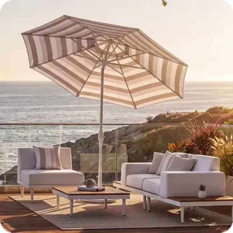 Striped patio umbrella shading a modern outdoor seating area with ocean views.