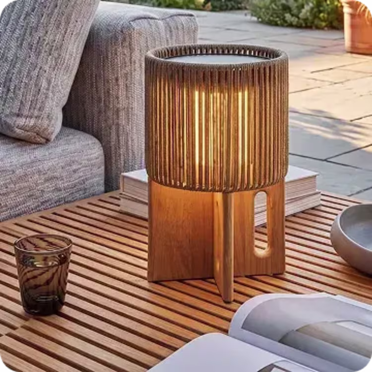 Outdoor lantern on a teak coffee table beside a cushioned sofa.