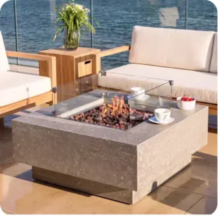 Modern rectangular fire pit table with glass wind guard on a coastal patio seating area.