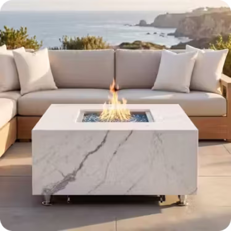 Contemporary marble-look gas fire table in front of an outdoor sectional sofa overlooking the ocean.