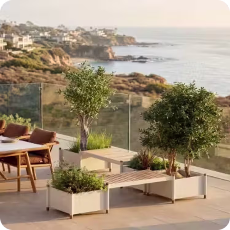 Modern outdoor planter boxes with trees and built-in bench seating overlooking the ocean.