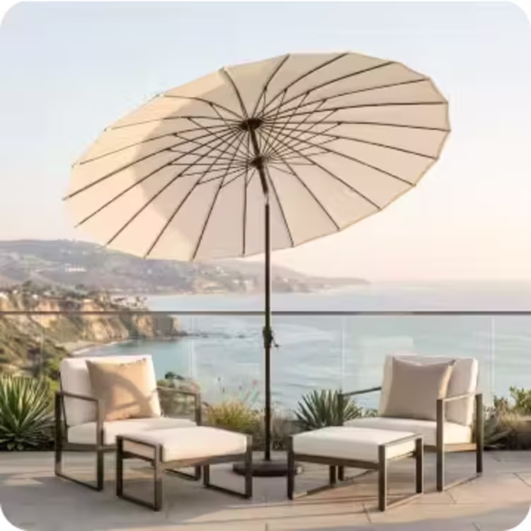 Two contemporary lounge chairs beneath a large market umbrella overlooking the ocean.