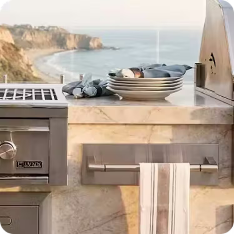 Contemporary outdoor kitchen countertop with built-in towel holder, grill, and prep area overlooking the ocean.