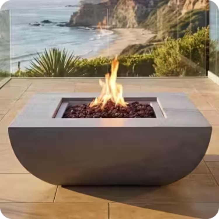 Square fire pit with flames on a coastal patio overlooking the ocean.
