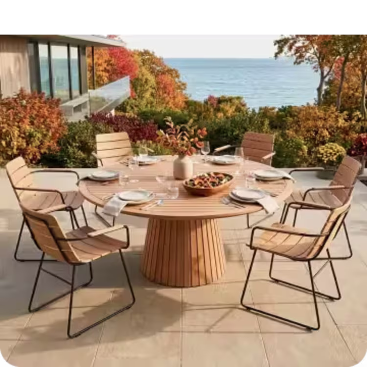 Round outdoor dining table and chairs set for a meal overlooking the autumn coastline.