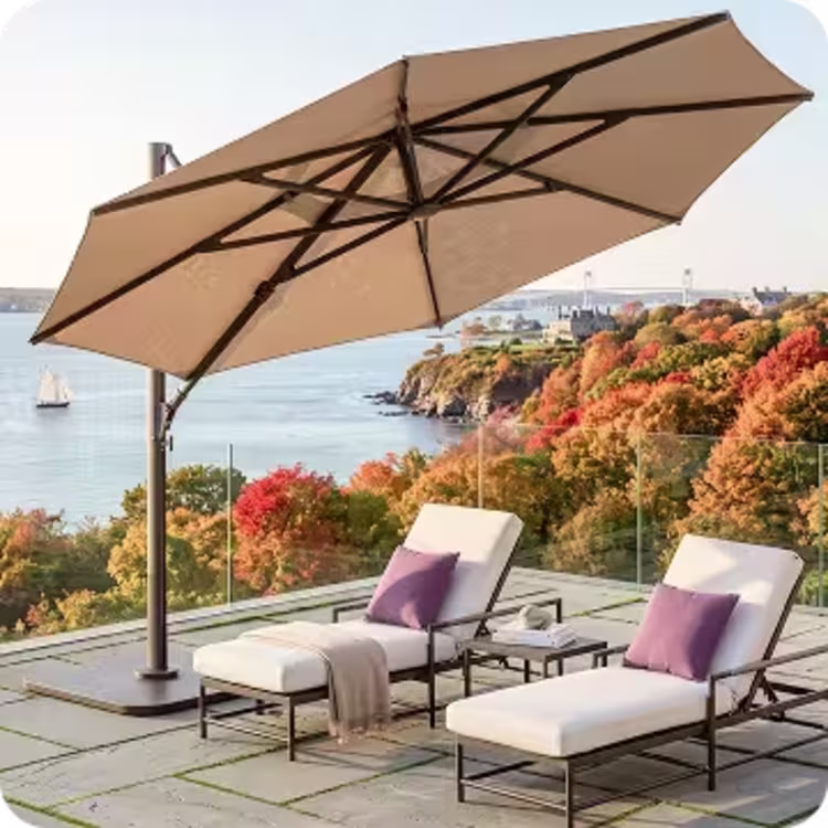 Cantilever umbrella shades two cushioned chaise lounges on a coastal patio.