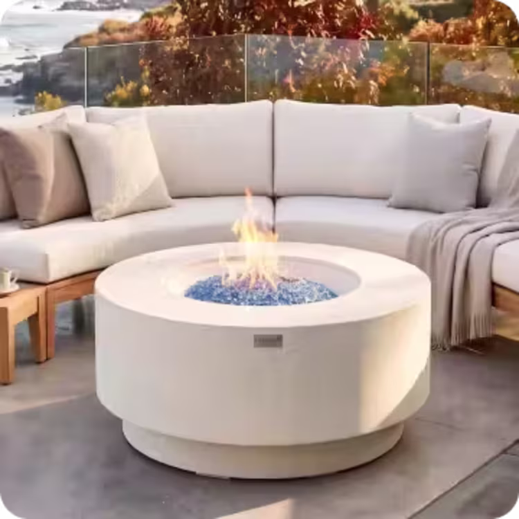 Round fire pit with blue glass surrounded by a curved cushioned outdoor sectional.