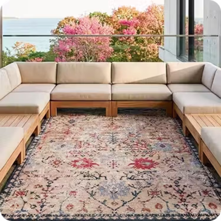 Patterned outdoor area rug beneath a neutral sectional on a coastal patio.