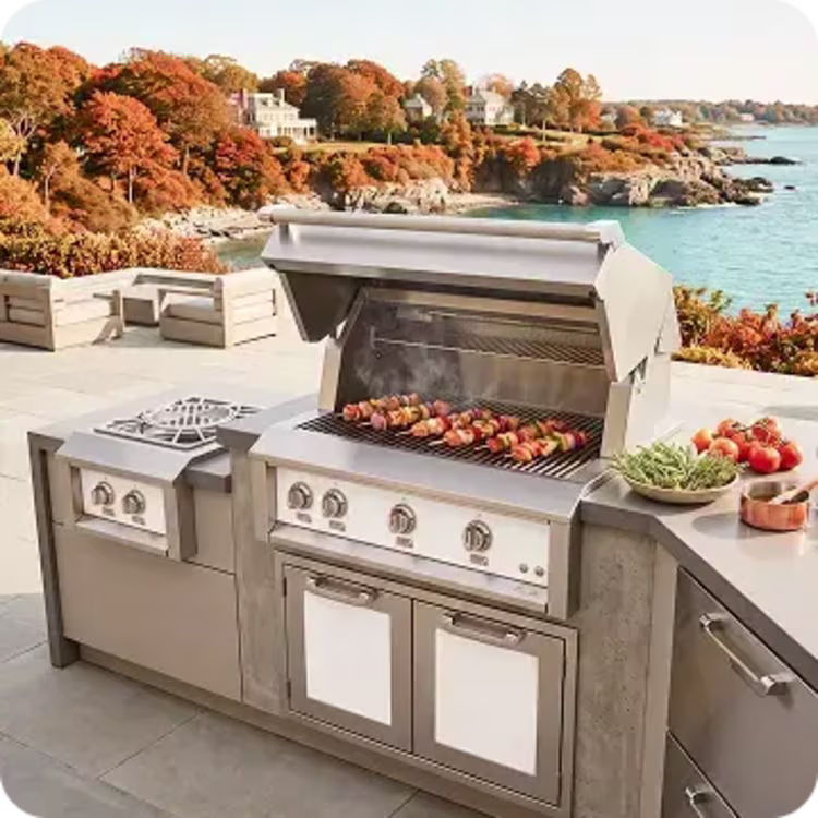 Outdoor kitchen and grill with food cooking against a fall coastal backdrop.