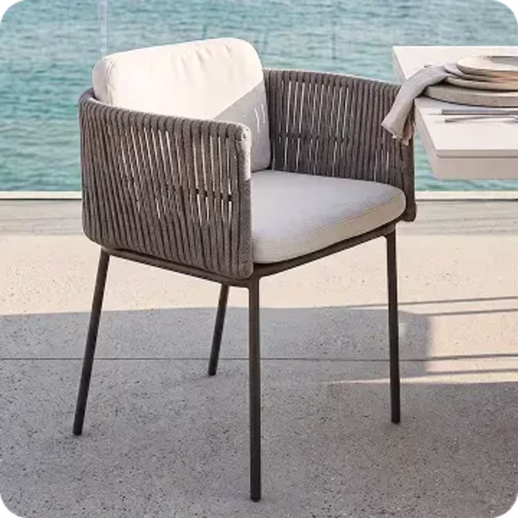 Woven outdoor dining chair beside a modern dining table overlooking the water.