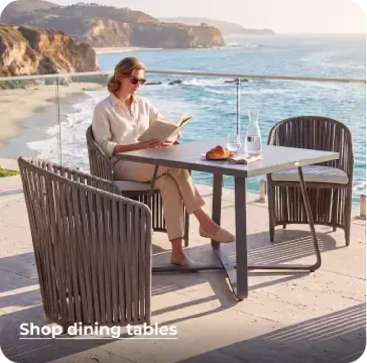 Woman reading at a modern outdoor dining table with coastal views.
