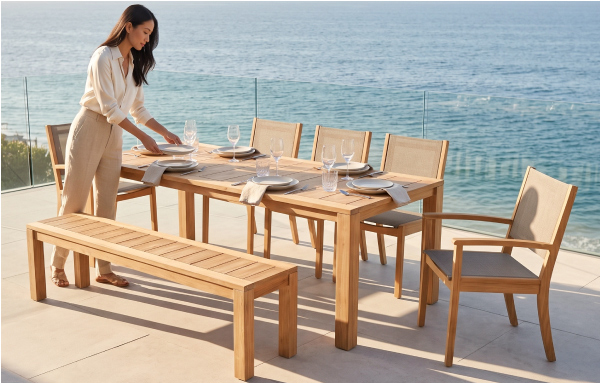 Woman setting the POVL Outdoor Foundation Calera dining set on a coastal patio