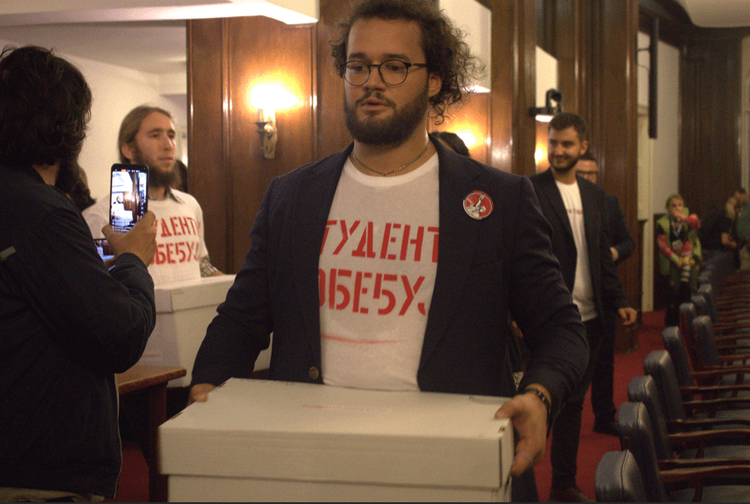 A student carries a white box containing documentation during the submission of the Student List at the Republic Electoral Commission