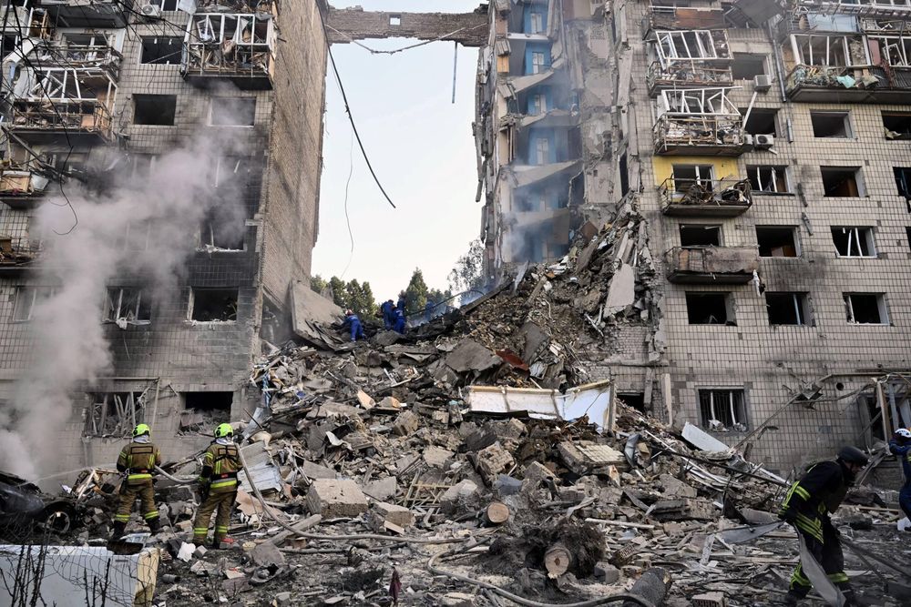 Rescue workers and firefighters beside the ruins of a residential building in Kyiv following a missile attack on 2 January 2024.